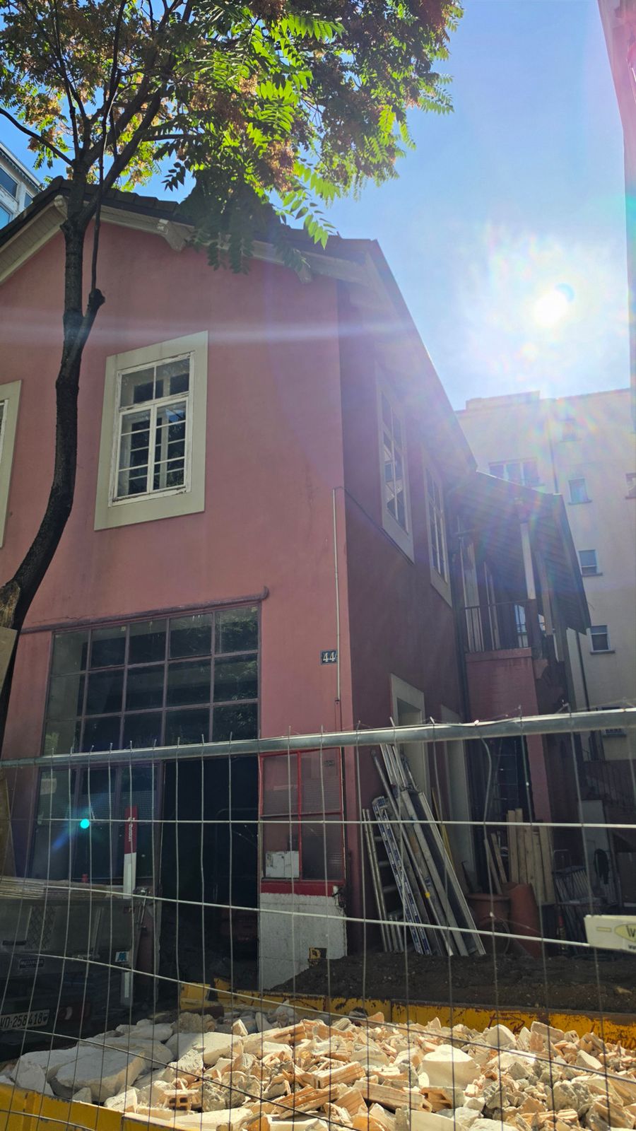 The pink facade of the Lausanne house behind the works fence