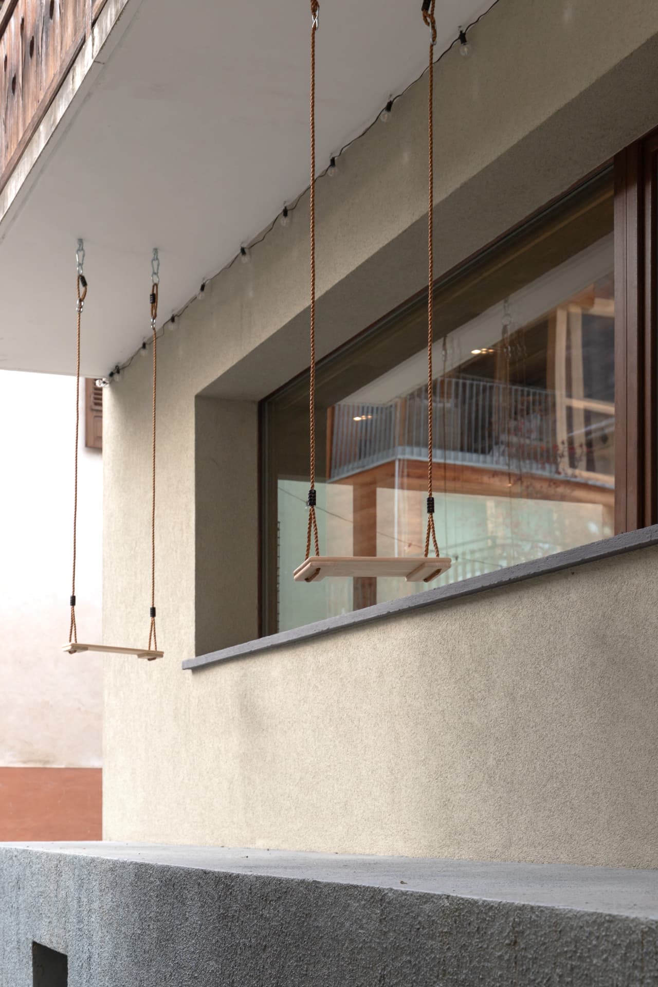 Two wooden swings hanging under the balcony at SoHome Le Châble
