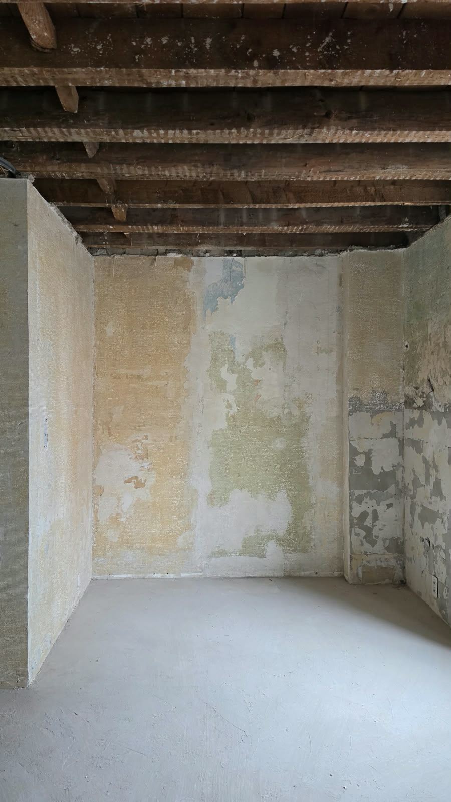 A bare room with exposed beams and layered plaster at SoHome Lausanne