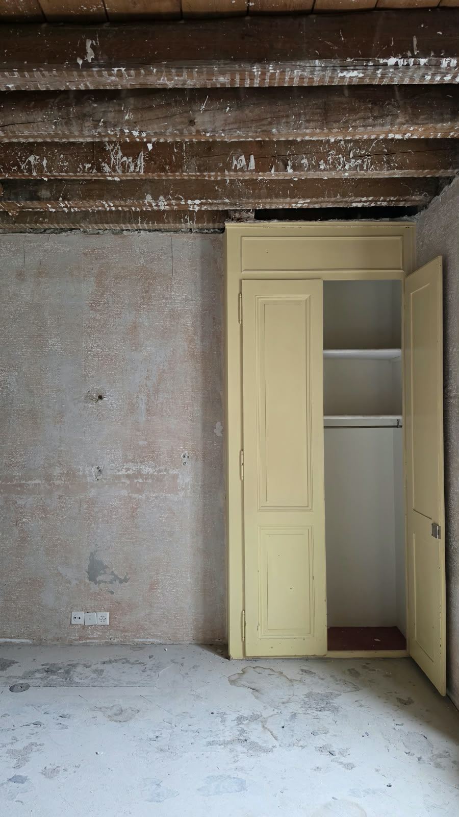 An original yellow-painted cupboard in an emptied room at SoHome Lausanne