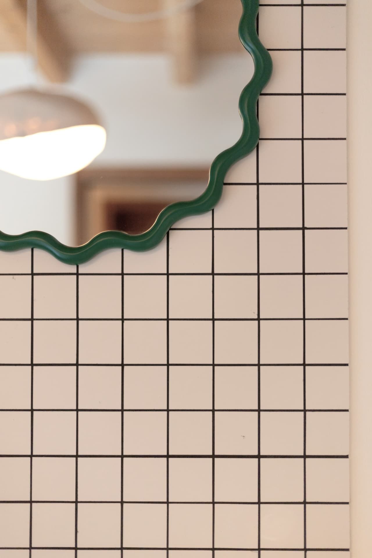 The wavy green mirror over white tiles in a bathroom at SoHome Le Châble