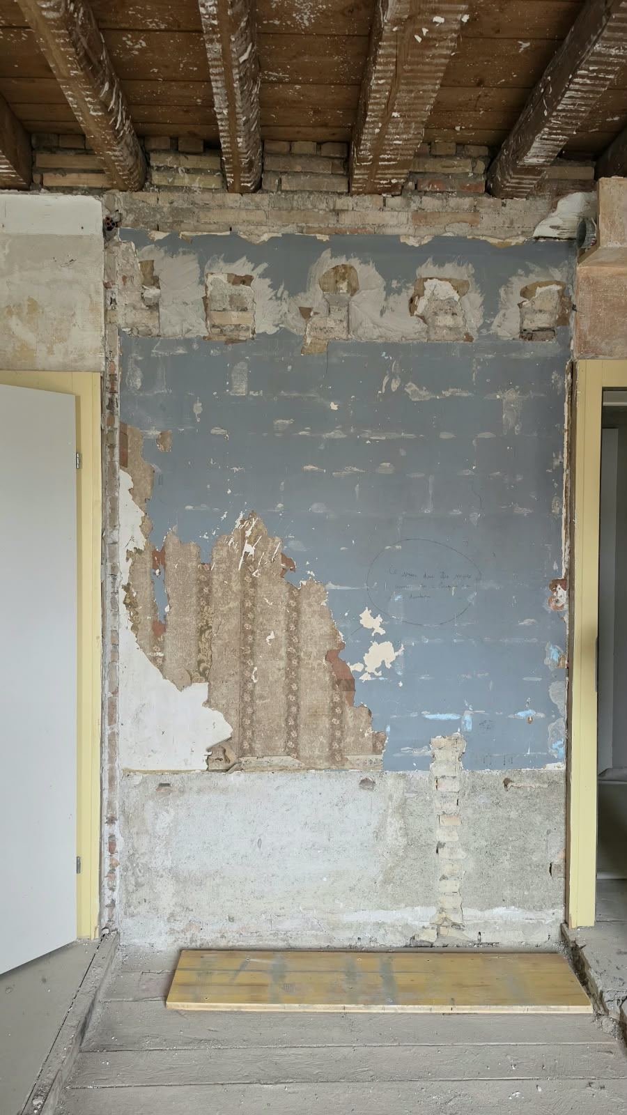 A wall revealing blue paint and old wallpaper layers at SoHome Lausanne