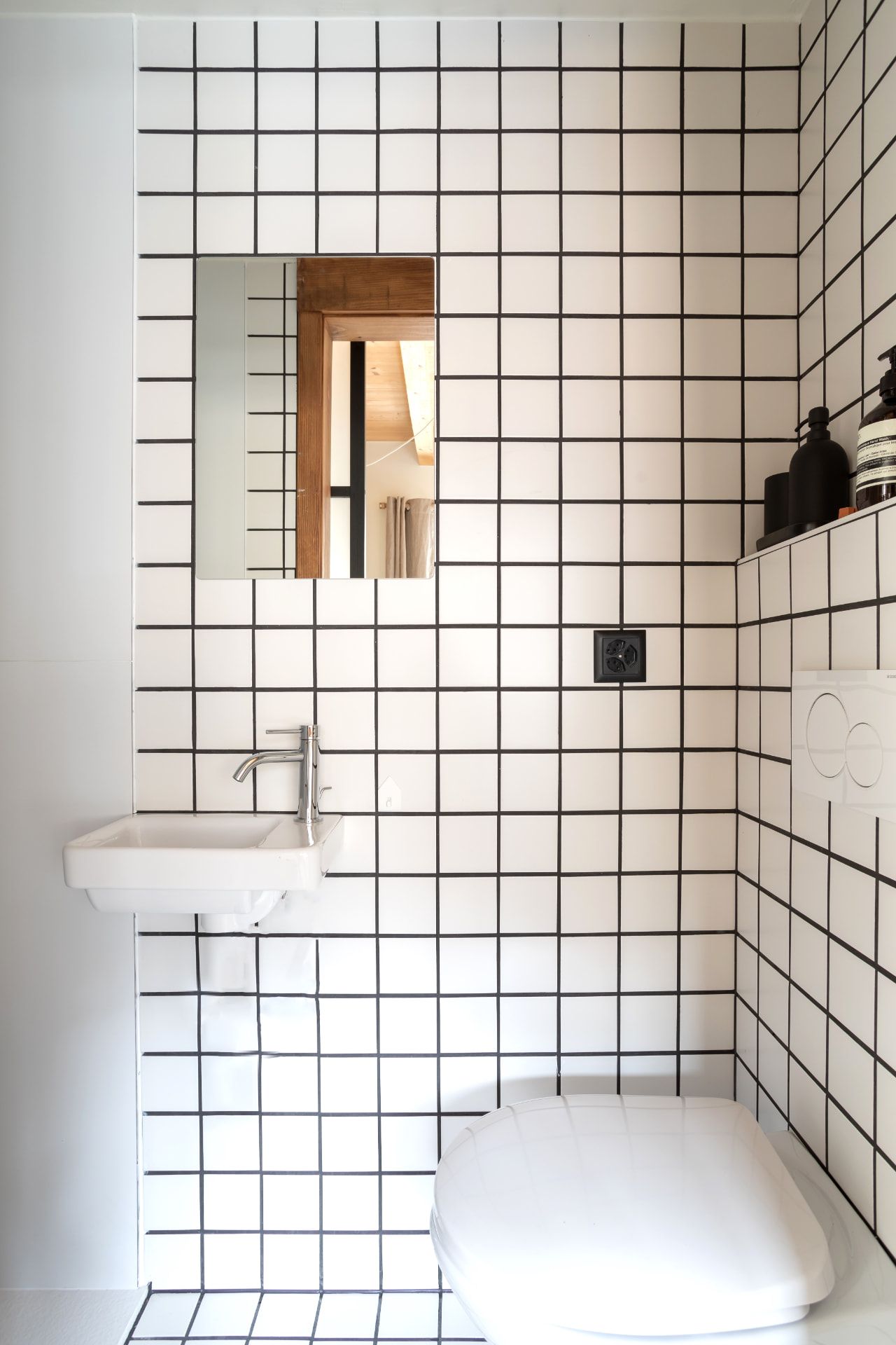 A bright washroom in white grid tiles at SoHome Le Châble