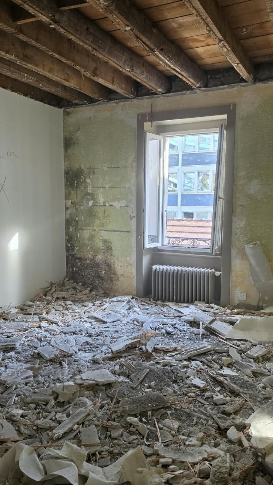 An emptied room with original beams and radiator at SoHome Lausanne