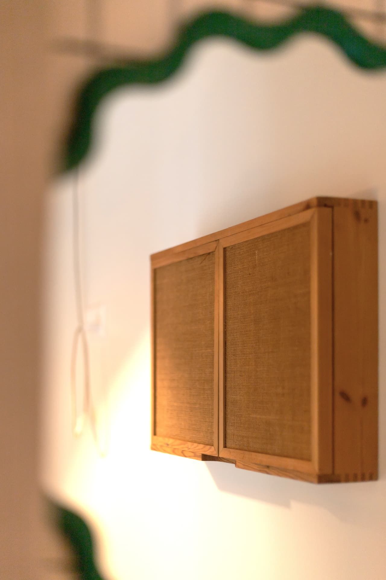 A wooden cabinet lit by a warm lamp in a bathroom at SoHome Le Châble